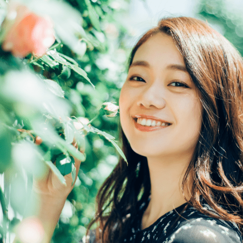 植物の横で微笑む女性