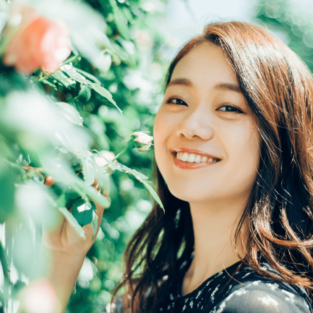 植物の横で微笑む女性