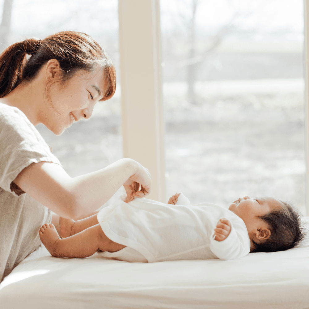 赤ちゃんを着替えさせるお母さん